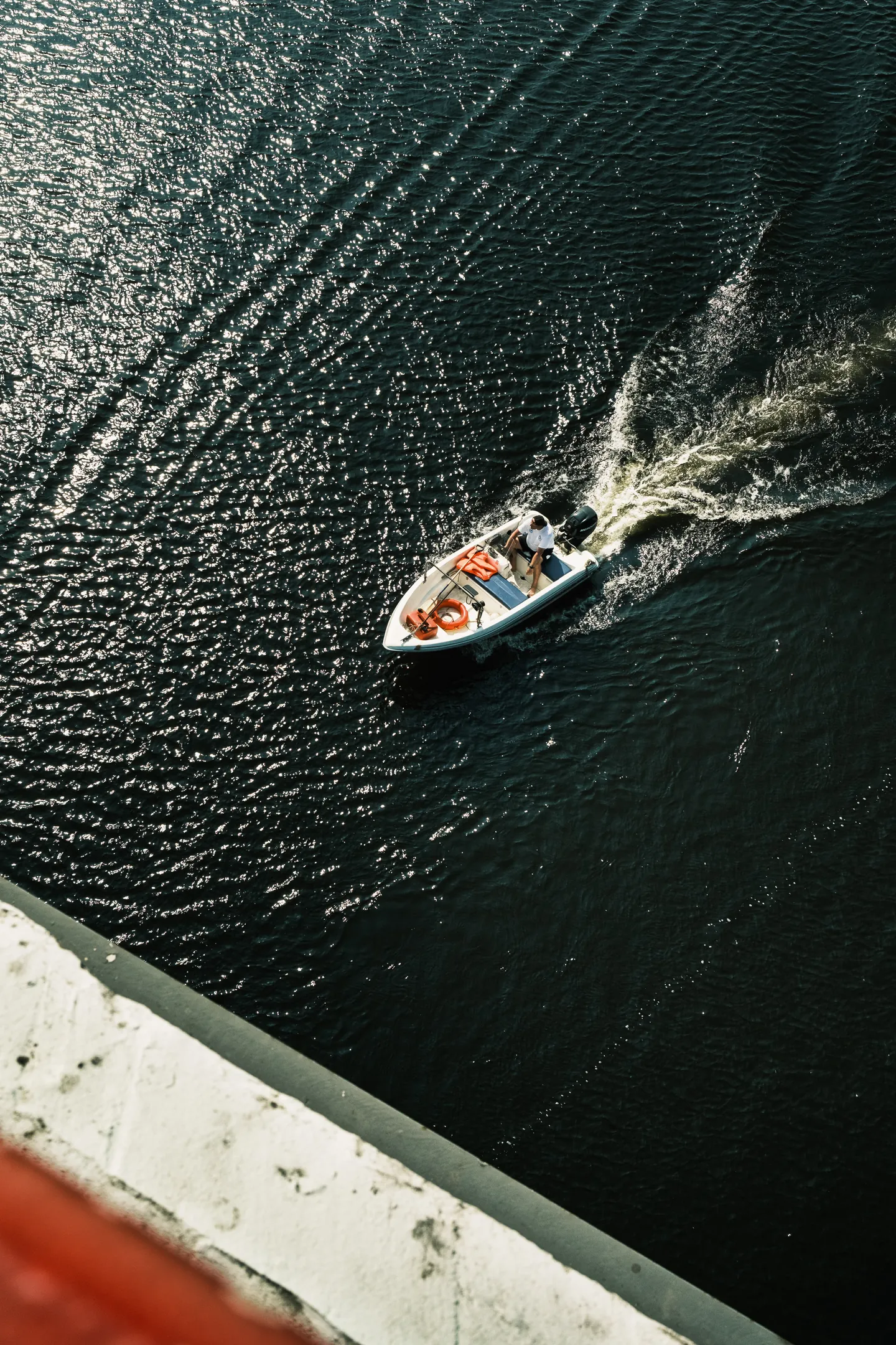 A motorboat crosses the Dnipro, leaving a trail through the sunlit water.