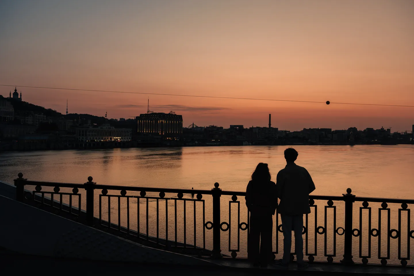 A couple watches the river at dusk.