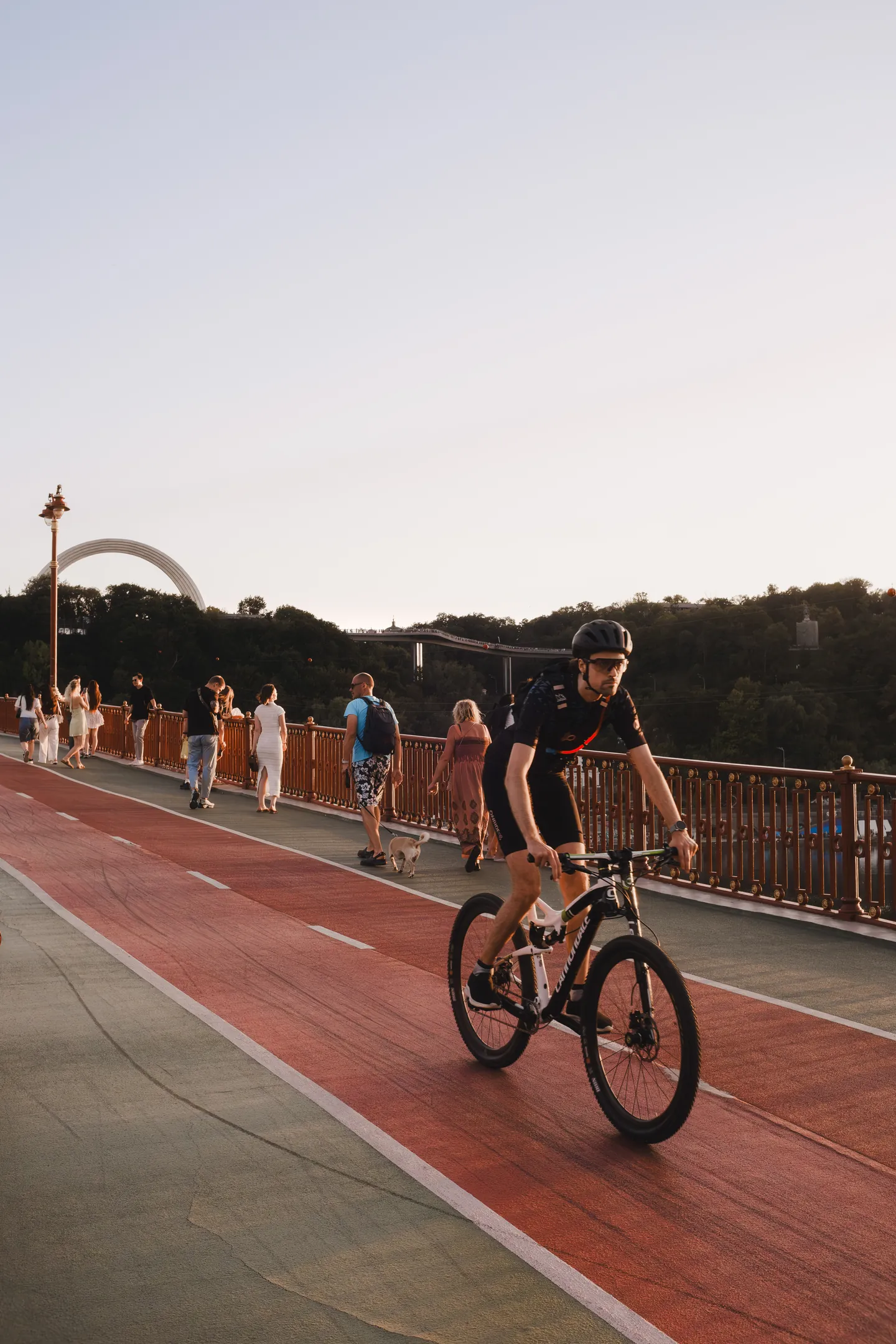 A cyclist passes pedestrians in the evening light.