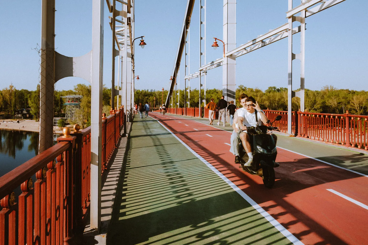 Scooter riders and pedestrians cross Kyiv’s Pedestrian Bridge.