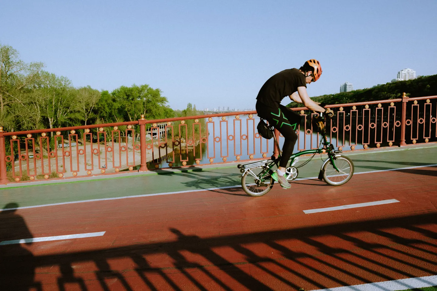 A cyclist rides a folding bicycle across the bridge.
