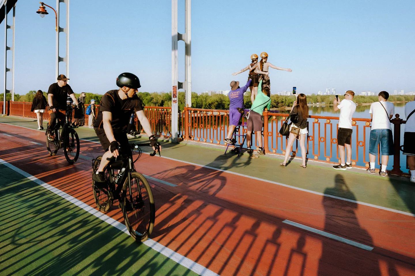 A cyclist looks towards people preparing for a rope jump on Kyiv’s Pedestrian Bridge.